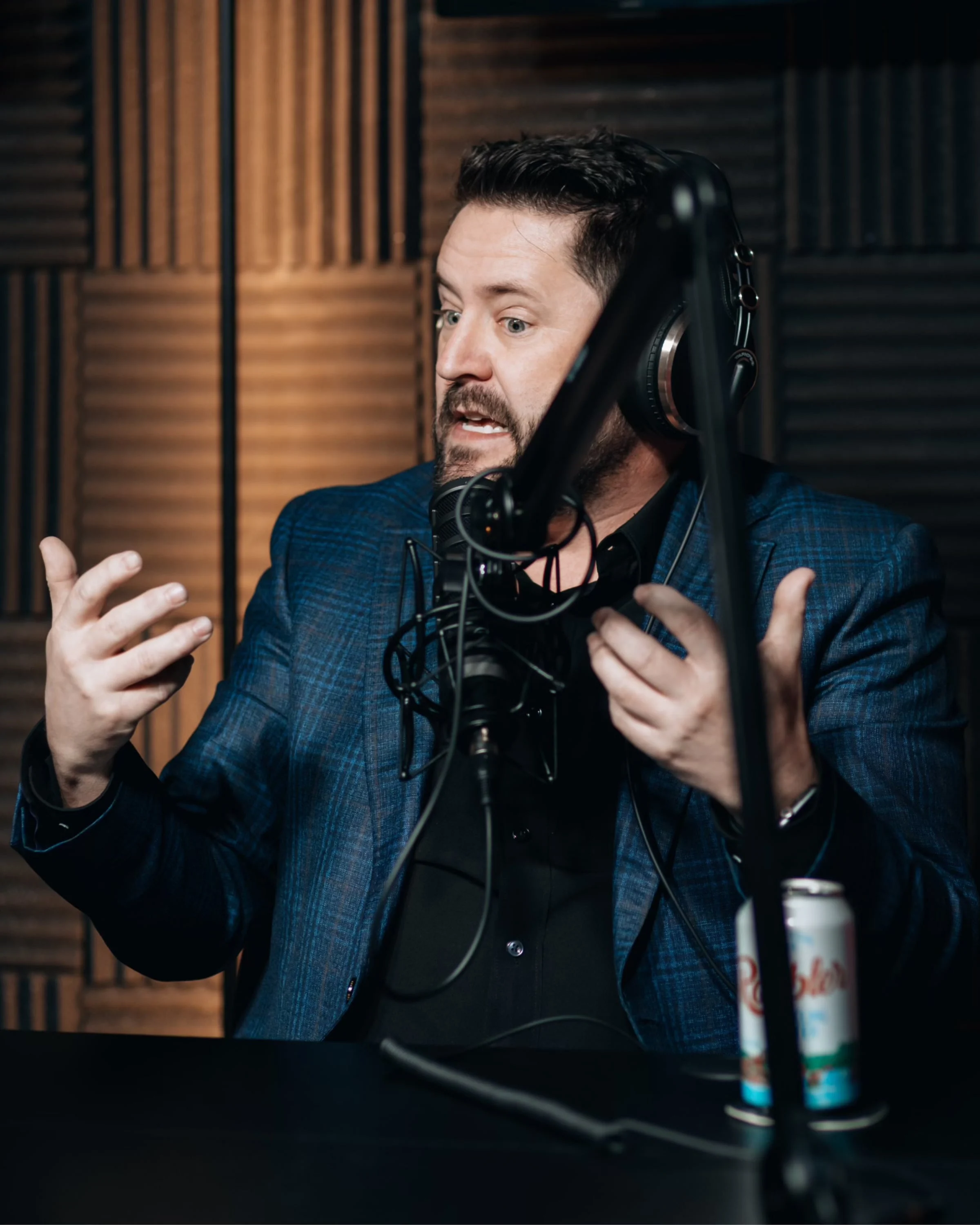 Wayne Salmans gesturing with both hands in a podcast studio