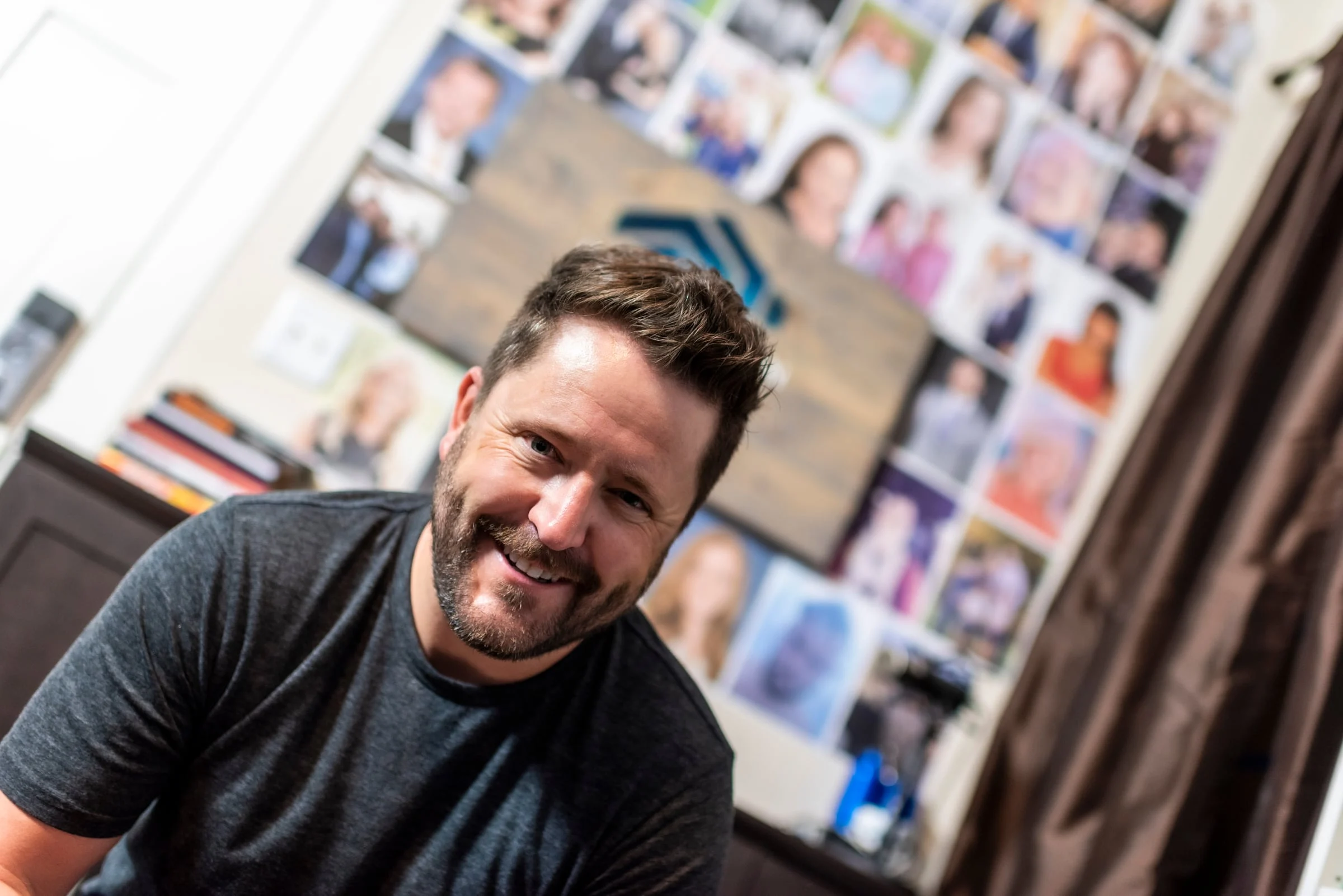 Wayne Salmans in front of a wall of team headshots